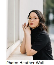 Trang Thanh Tran in black top leaning on wall by window photographed by Heather Wall Photography